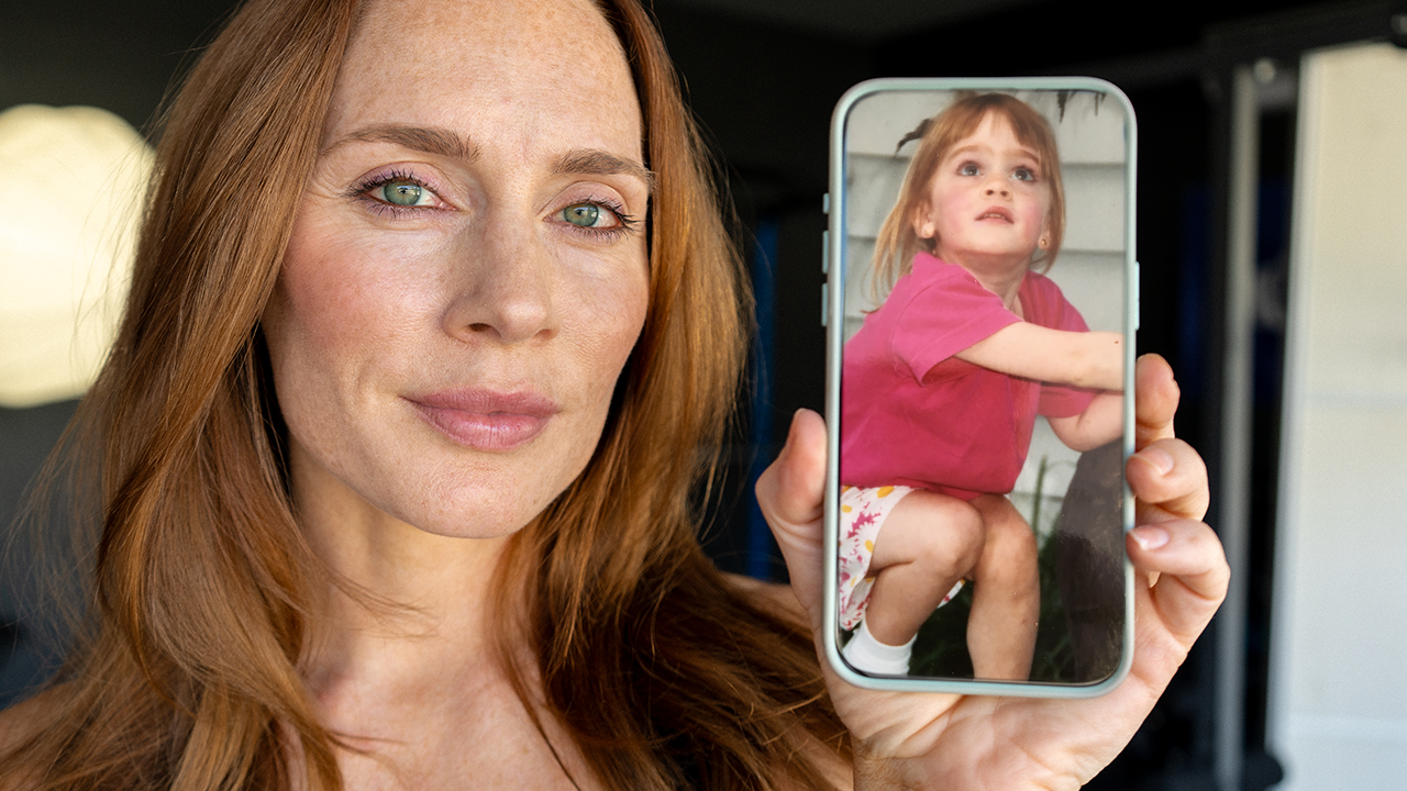 Meg Squats holding a phone displaying a childhood photo of herself, reflecting on body image and confidence